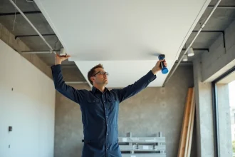 Installateur professionnel posant un plafond tendu blanc dans un local commercial en rénovation