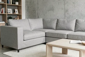 Protège canapé d'angle ajusté en tissu gris sur un canapé en L dans un salon moderne au style scandinave