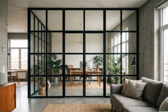 Verrière type atelier en acier noir séparant un salon et un bureau dans un appartement moderne au style industriel scandinave
